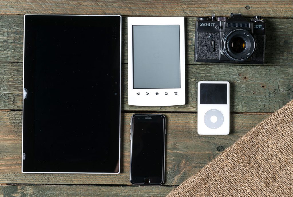 Digital devices displayed on a wood table surface.