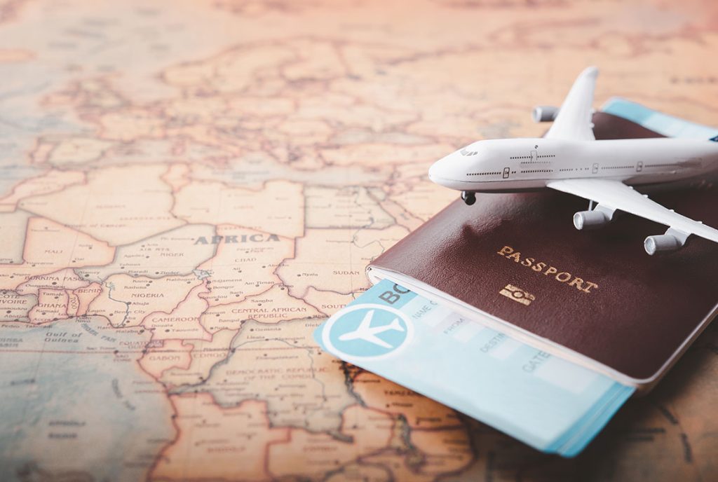 Passport with airline ticket and a model aircraft on top displayed on a map of Africa.